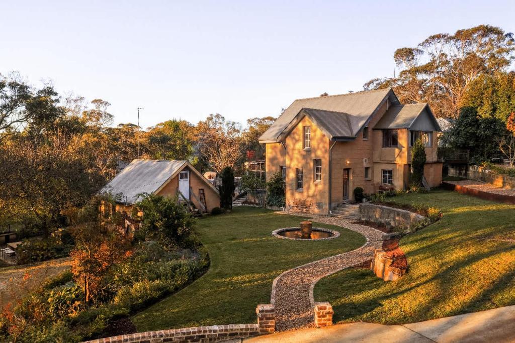 a large house with a yard with a stone pathway at Harvest Cottage Blue Mountains in Leura