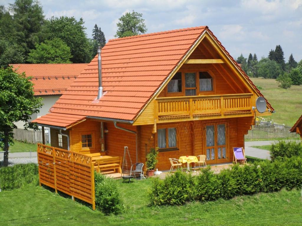 ein Holzhaus mit einem orangenen Dach auf einem Hof in der Unterkunft "kleines jagdhaus"- Hüttenurlaub in Bayern in Philippsreut