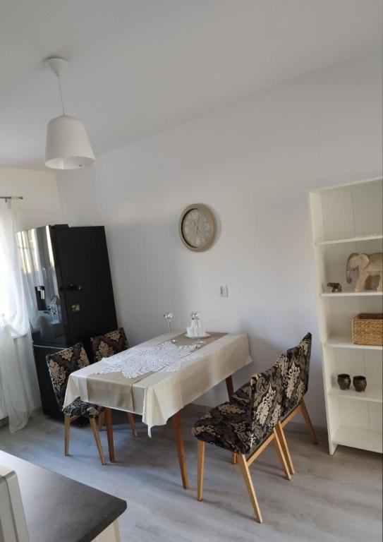 a dining room table with chairs and a clock on the wall at Dana in Sokołowsko