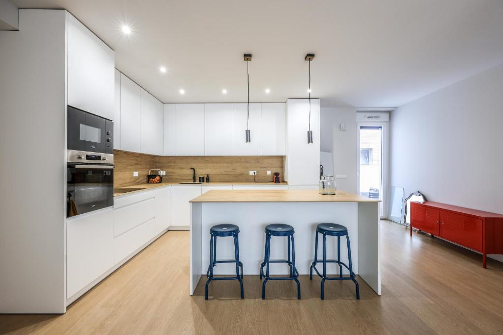 a kitchen with white cabinets and a island with two bar stools at Spacious Home with Private Garden and Parking in Madrid