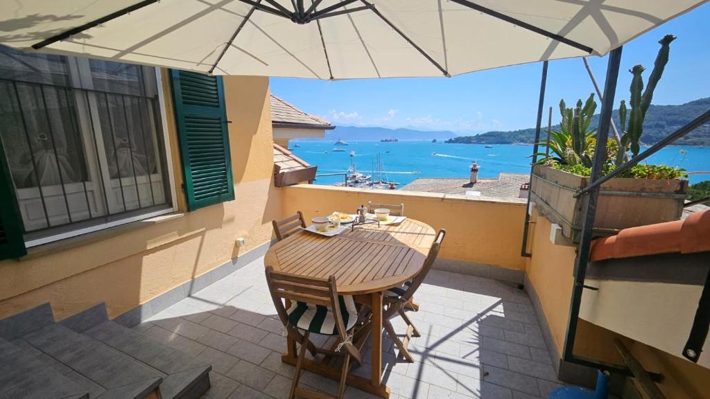 a table and chairs on a balcony with an umbrella at Ampia casa marinara con meravigliosa terrazza vista mare Da Mario e Rosanna in Portovenere