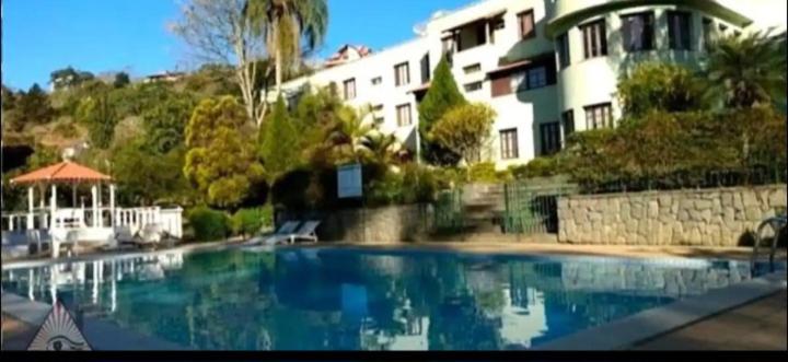 a large swimming pool in front of a building at Flat - Condomínio Summerville Apart in Miguel Pereira