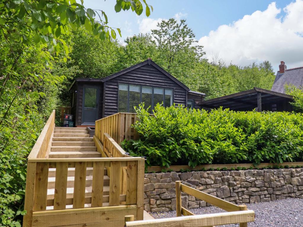 a house with a wooden staircase leading up to a building at Lodge at Nadur in Machynlleth