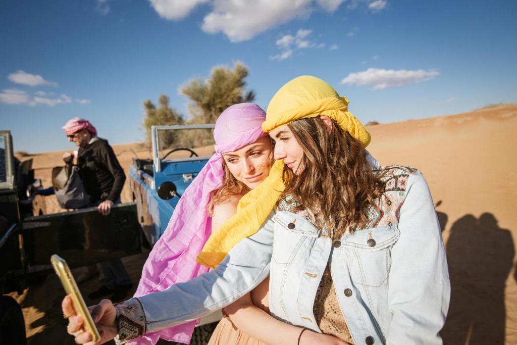 two women wearing turbans standing in the desert at Merzouga Luxury Camping in Merzouga