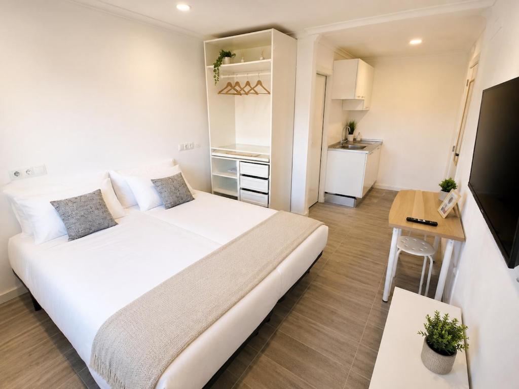 a bedroom with a large white bed and a kitchen at Exclusive Studio Kitchenette e WC Privativo in Abrantes