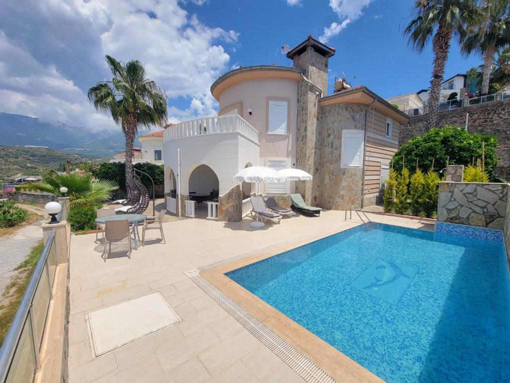 a villa with a swimming pool in front of a house at Jasminpark Villa in Alanya