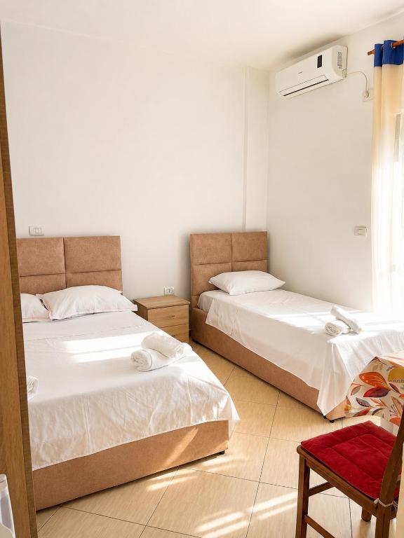 a bedroom with two beds and a chair and a window at Amarildo Rooms in Durrës