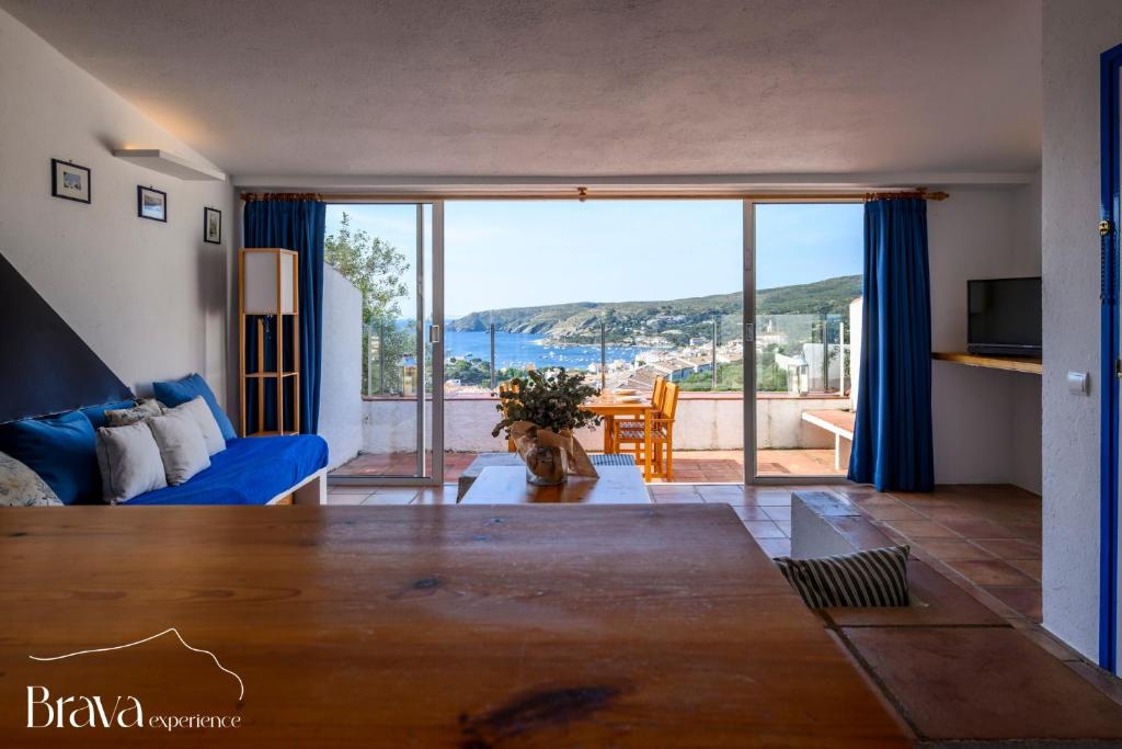 a living room with a blue couch and a large window at Can Rino - Vistas panorámicas I piscina I tenis I terraza I Brava Experience in Cadaqués