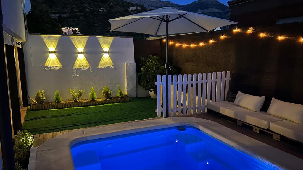 a backyard with a pool and a couch and an umbrella at Balcón de Mágina in Torres