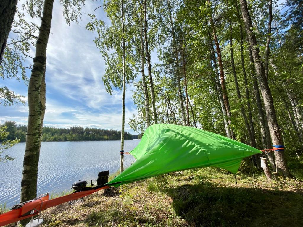 a green tent on the side of a lake at Tree Tents Camping Linnansaari in Savonlinna