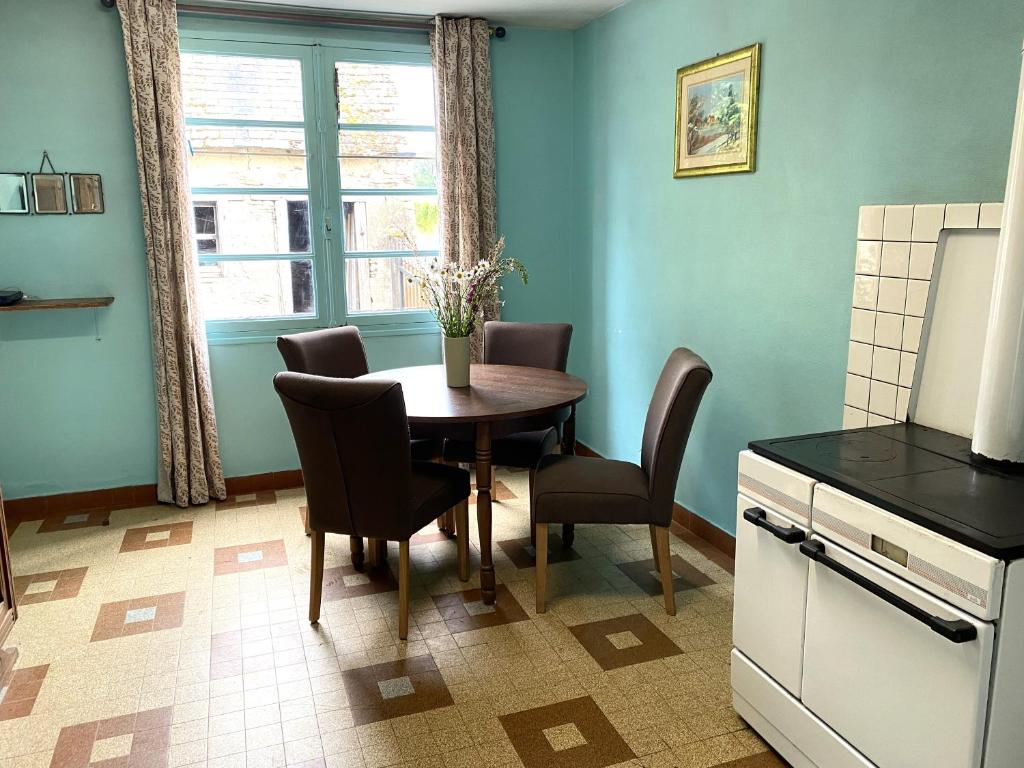 a kitchen with a table and chairs and a window at Maison Le Merle Rouge in Sazeray
