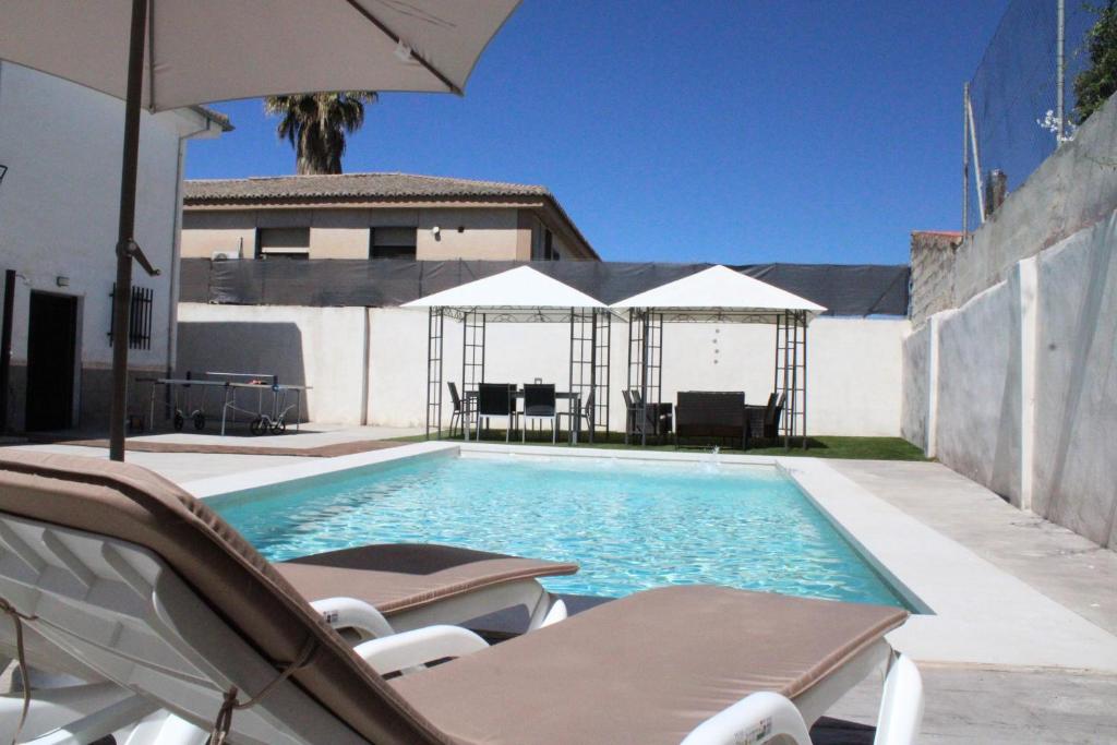 a swimming pool with chairs and umbrellas next to a building at Can Guzmu in Cijuela