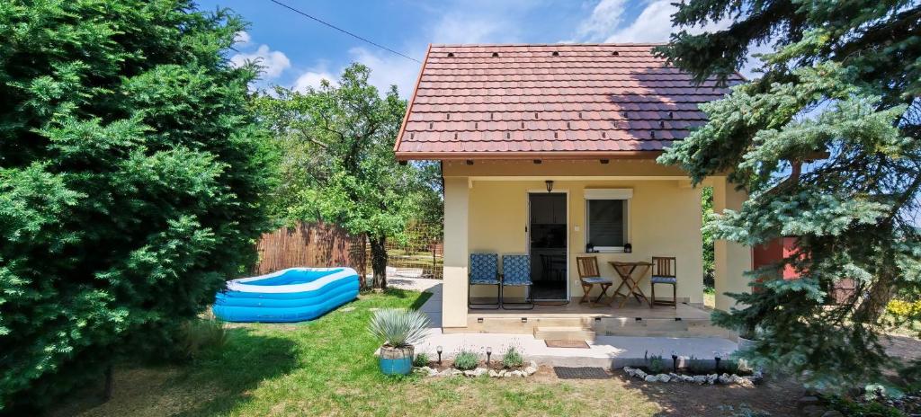 a small yellow house with a blue boat in the yard at Ezüstfenyő vendégház in Balatonalmádi