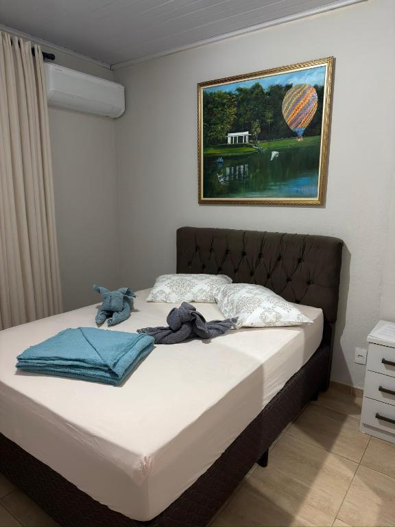 a bed in a bedroom with a painting on the wall at Cantinho do Aconchego in São Lourenço