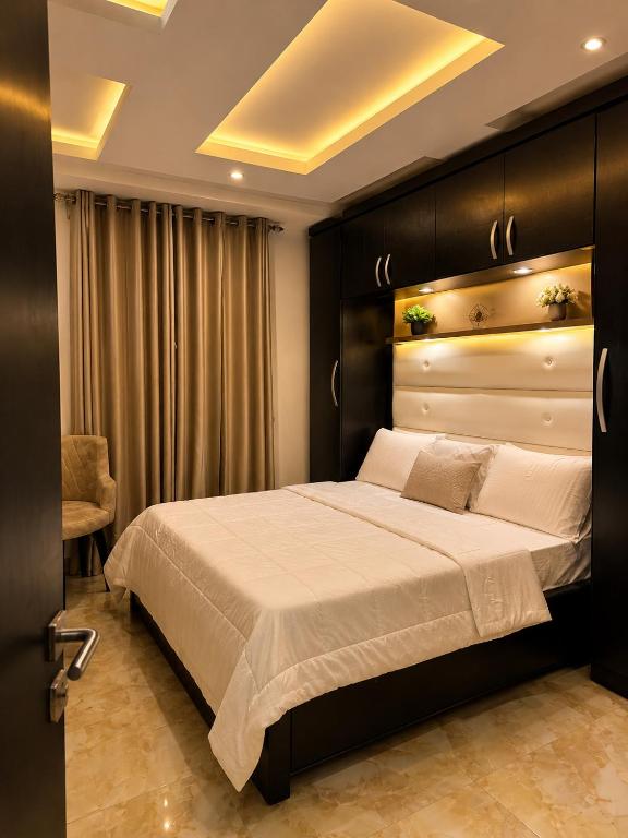 a bedroom with a large bed with a black headboard at Restnest suite in Benin City