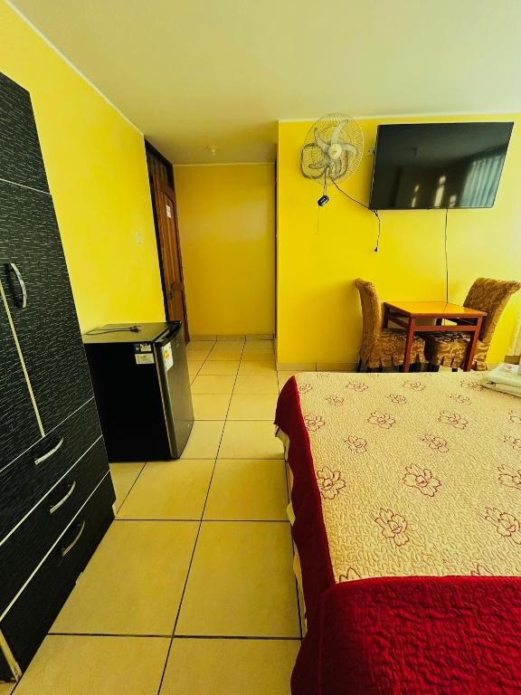 a bedroom with a bed and a kitchen with a fan at Sandel Barranca Peru in Barranca
