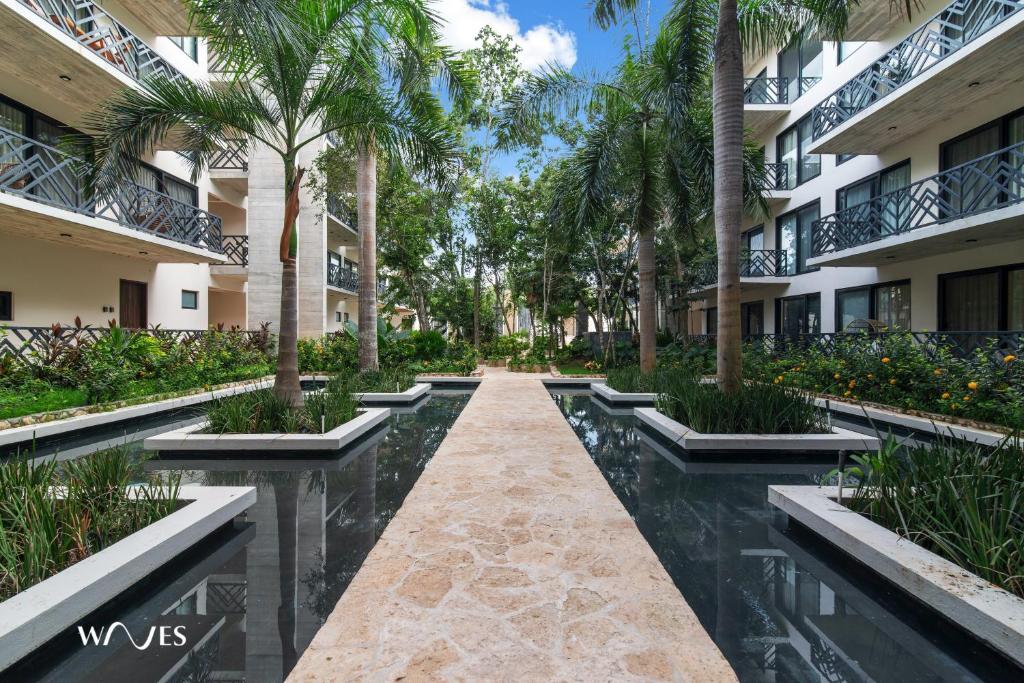 a walkway through the courtyard of a building with palm trees at Spacious Loft with Balcony Near Hotel Zone Palais Tulum by Waves in Tulum