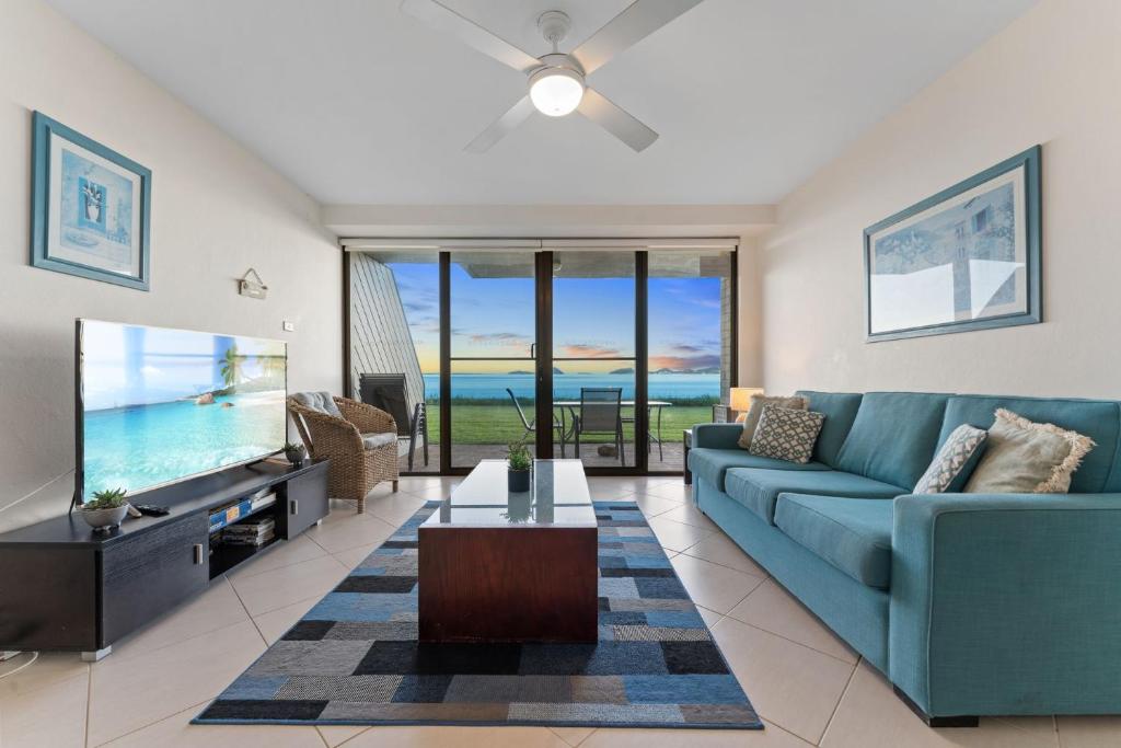 a living room with a blue couch and a flat screen tv at Harbourside Unit 2 7 Soldiers Point Road in Soldiers Point