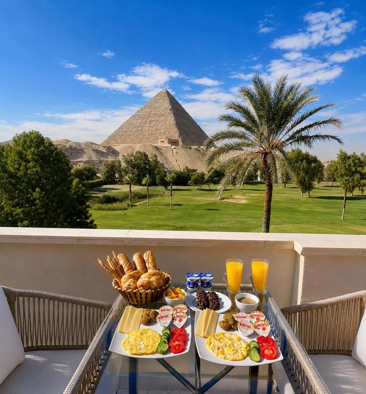 a tray of food on a balcony with a pyramid in the background at Vincci Pyramids View in Cairo
