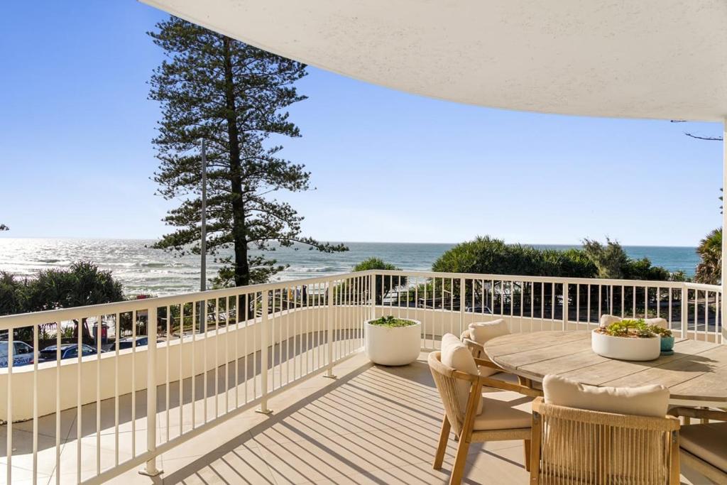 a deck with a table and chairs and the beach at 6 Baywatch Apartments in Coolum Beach