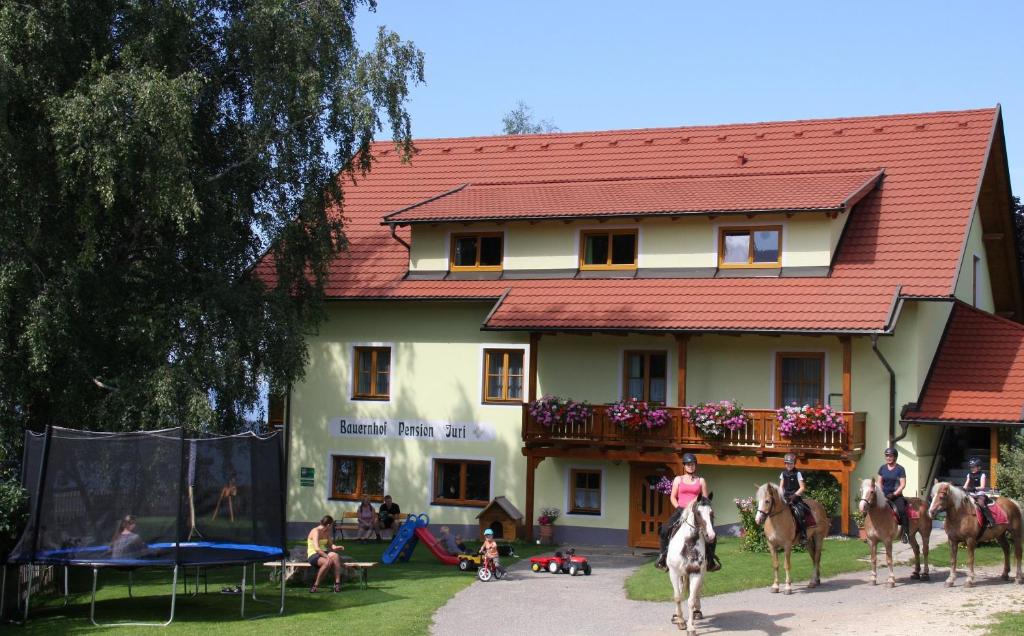 ObergöselにあるBauernhof Pension Juriの馬に乗る人々が目の前に立つ建物