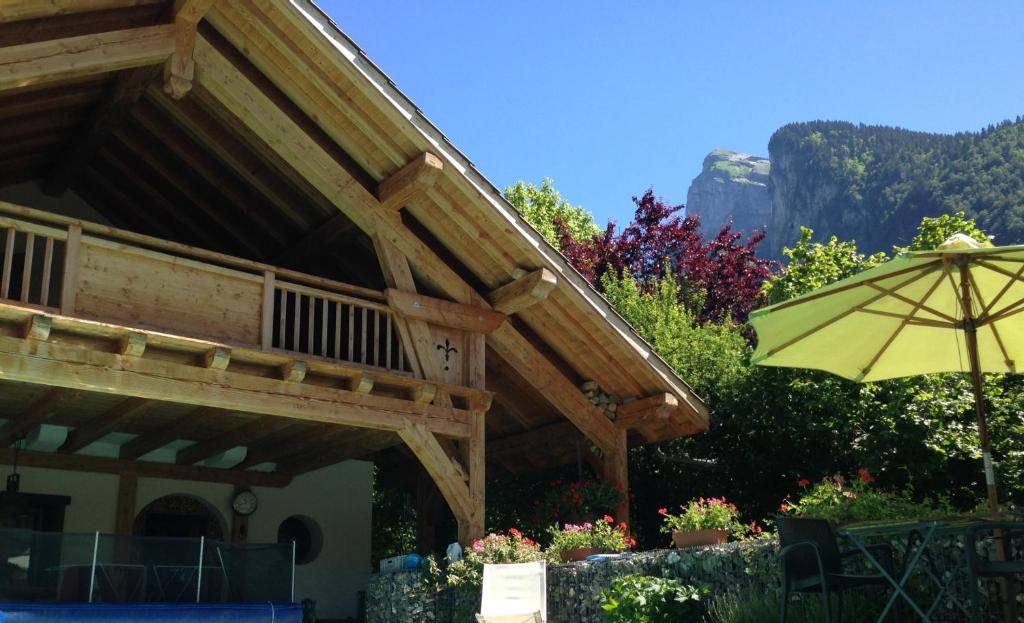 a wooden building with an umbrella and some flowers at Chambres d'hôtes de charme Douglas in Samoëns