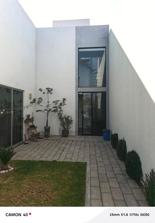 a white house with a courtyard with a glass door at Loft Privado Seguridad 24HRS a 15 de piramide de cholula in Cholula