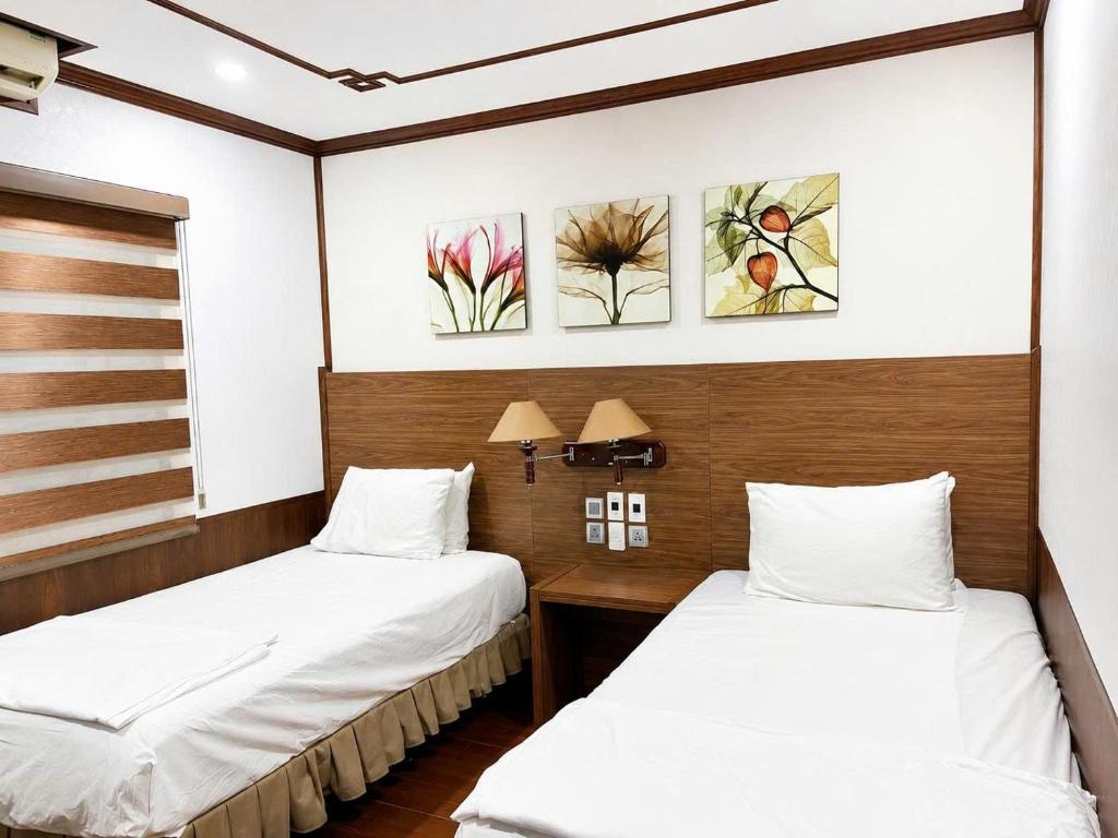 two beds in a room with white sheets at Khách Sạn Phú Hưng 2 in Hanoi