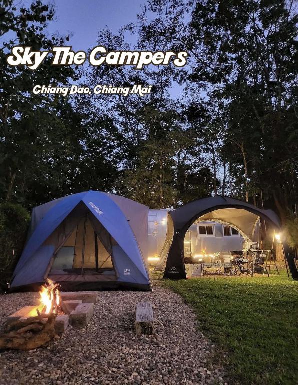 a tent and a campfire in a field at night at Sky The Campers in Chiang Dao