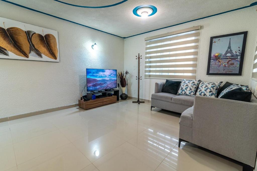 a living room with a couch and a flat screen tv at Cómoda Casa a 7 minutos de la playa in Ciudad Madero