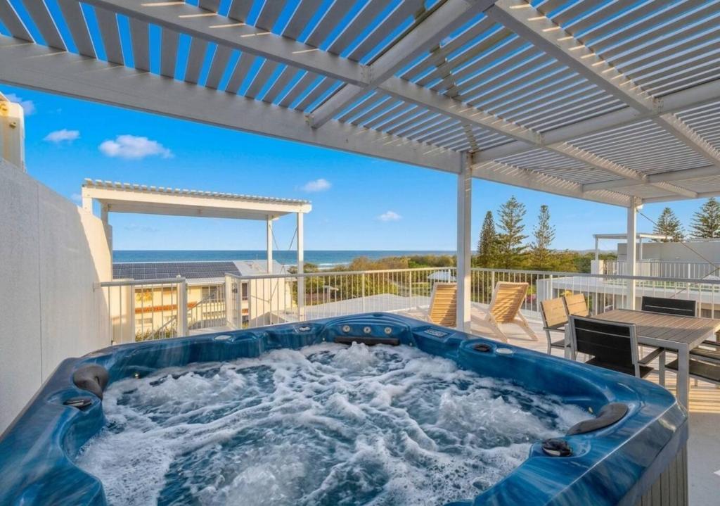 a hot tub on a patio with the ocean in the background at Beach Days, Ocean Rooftop & Spa - Sleeps 8 in Marcoola
