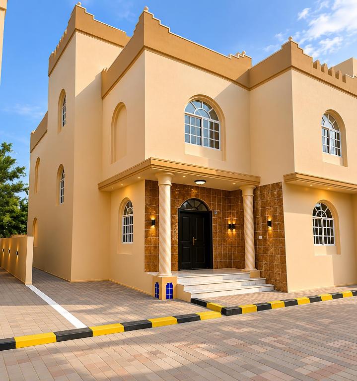 a large building with a black door and columns at Al Shorooq Residential Complex مجمع الشروق السكني in Salalah