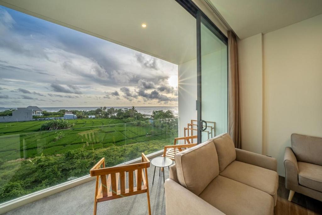 a living room with a couch and a large window at Horizon Cemagi 2BR with Ocean View in Cemagi