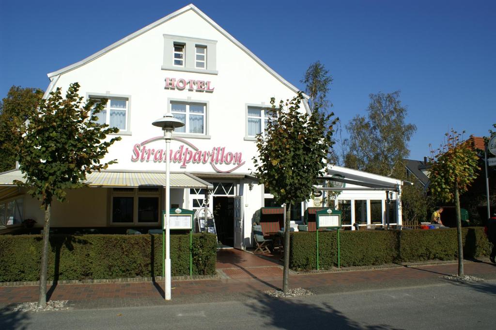 ein weißes Gebäude mit einem Schild davor in der Unterkunft Hotel Strandpavillon in Baabe