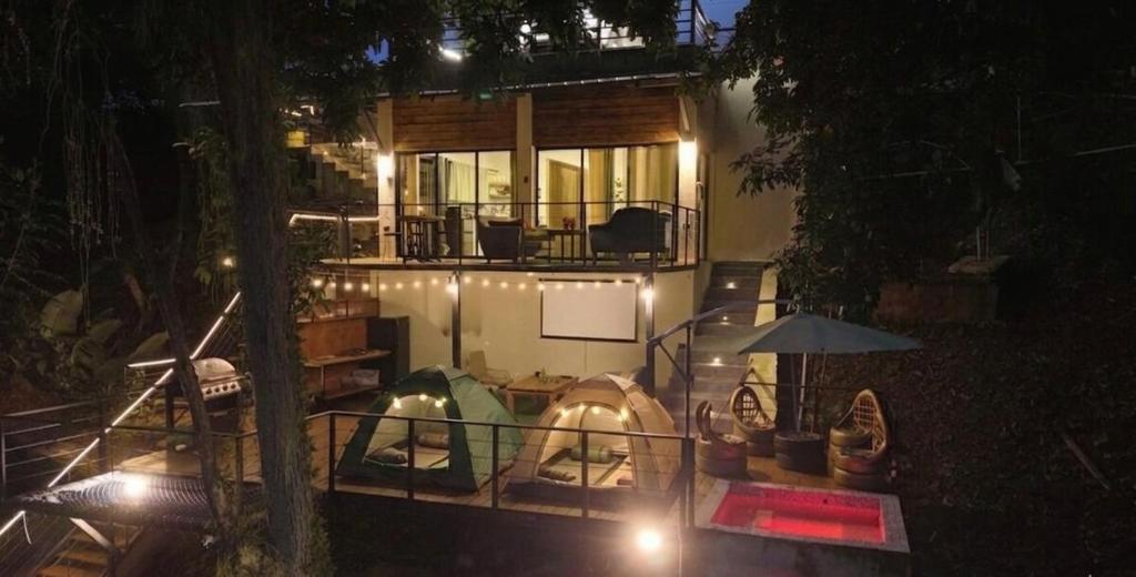 a house with a porch with tents and an umbrella at River View-Camping Add-On Available in Jarabacoa