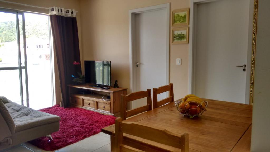 sala de estar con sofá, mesa y TV en Apartamento Cachoeira do Bom Jesus, en Florianópolis