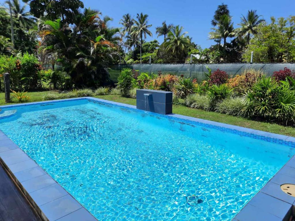 a swimming pool with blue water in a backyard with trees at Haven Retreat in Pacific Harbour
