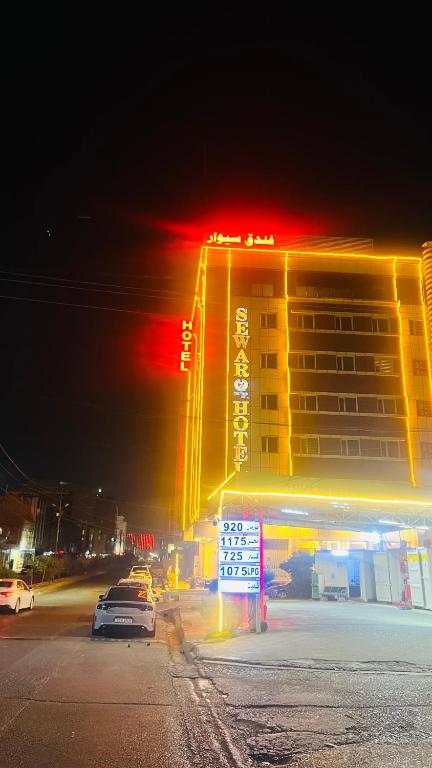 a hotel building at night with cars parked in front of it at فندق سيوار in Erbil