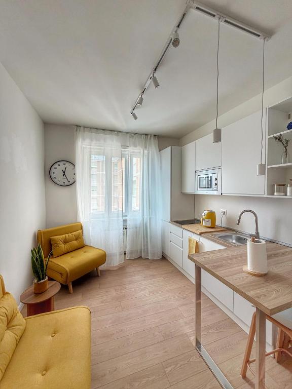 a kitchen with white cabinets and a table and a yellow chair at HOME PERLa in San Bartolomeo al Mare
