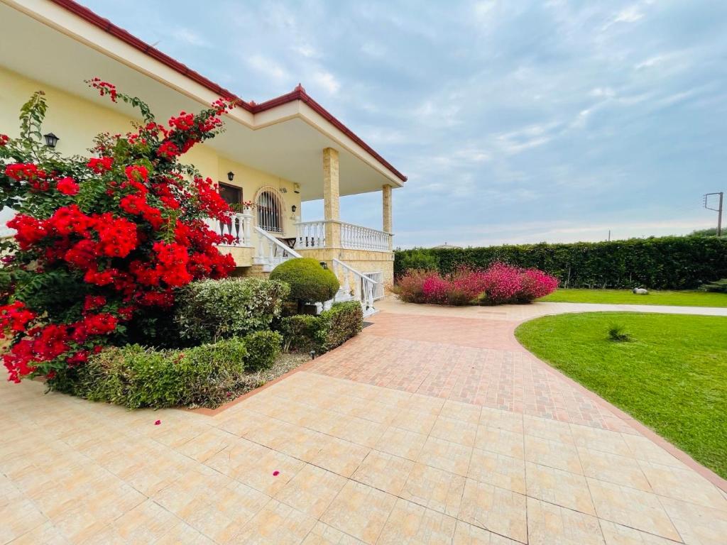 a house with red flowers and a walkway at The Greek Mama's Cottage in Epanomi