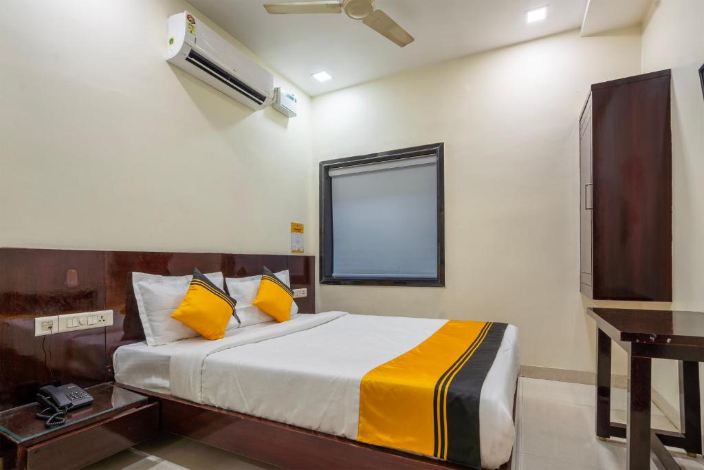 a bedroom with a bed with yellow pillows at Itsy Hotels M in Vijayawāda