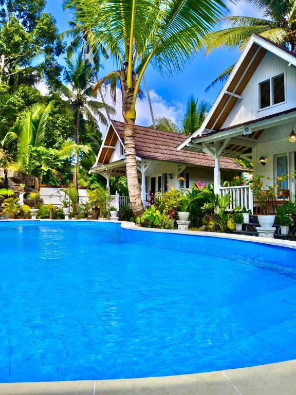 a large blue swimming pool in front of a house at Jalana Palm Villa in Tabanan