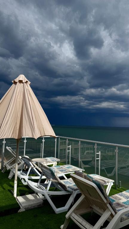 a group of lounge chairs and an umbrella and the ocean at Отель у моря Chester in Odesa