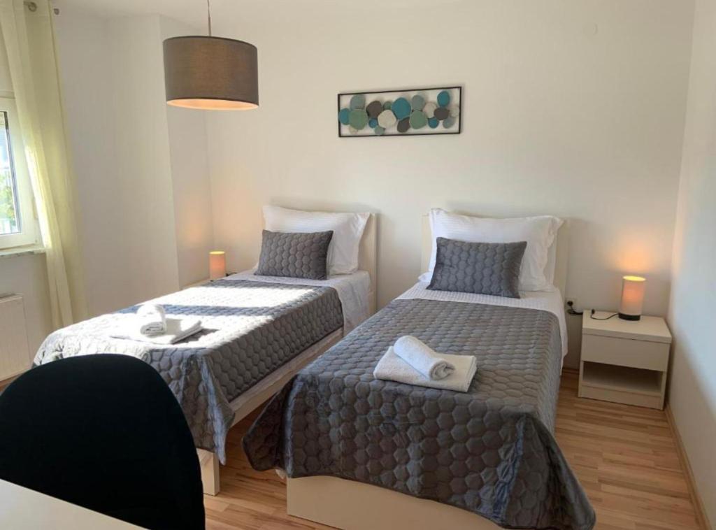 two beds in a small room with two lamps at Apartman Ivanka in Imotski