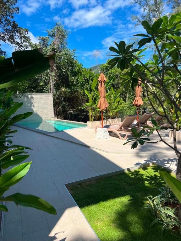 a swimming pool with two umbrellas next to a resort at Hidden Bay Chaloklam in Chaloklum