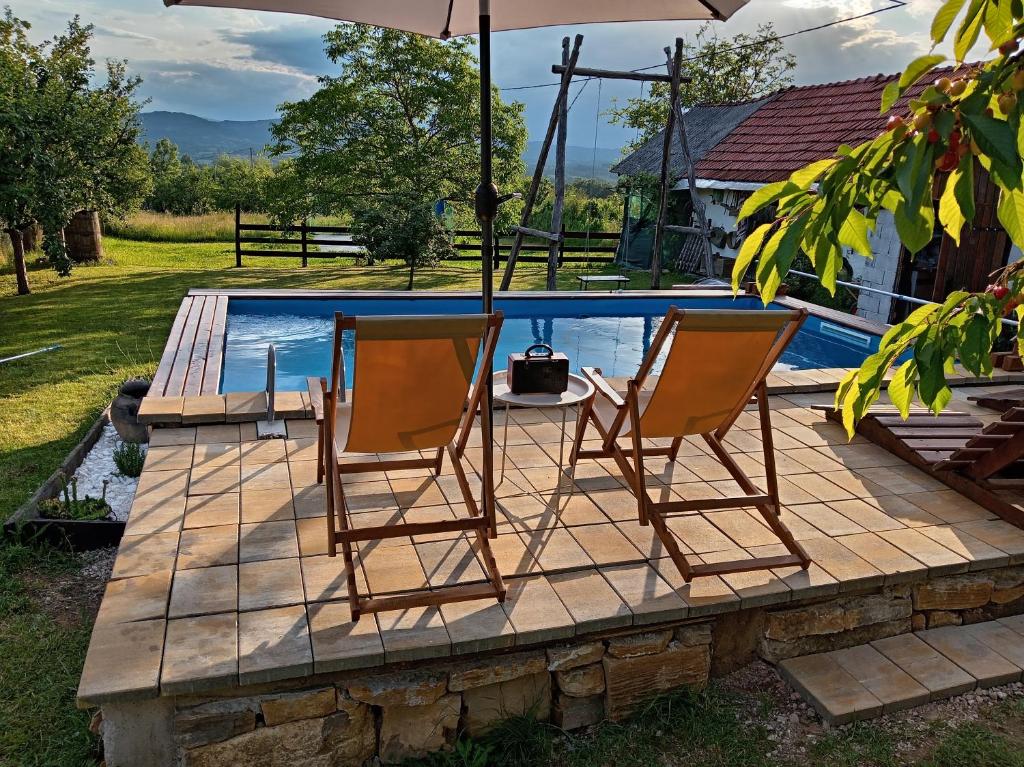two chairs sitting on a deck next to a swimming pool at ZOĆEVIĆA KONAK in Petrovići