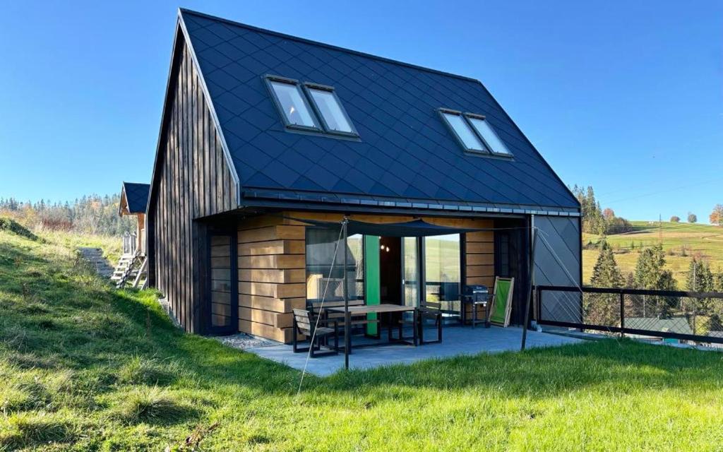 a barn style house with a patio and a table at Bystre DOMKI in Nowe Bystre