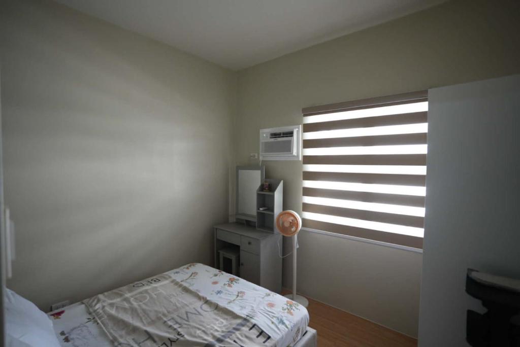 a small bedroom with a bed and a window at RSGH Staycation in Biñan