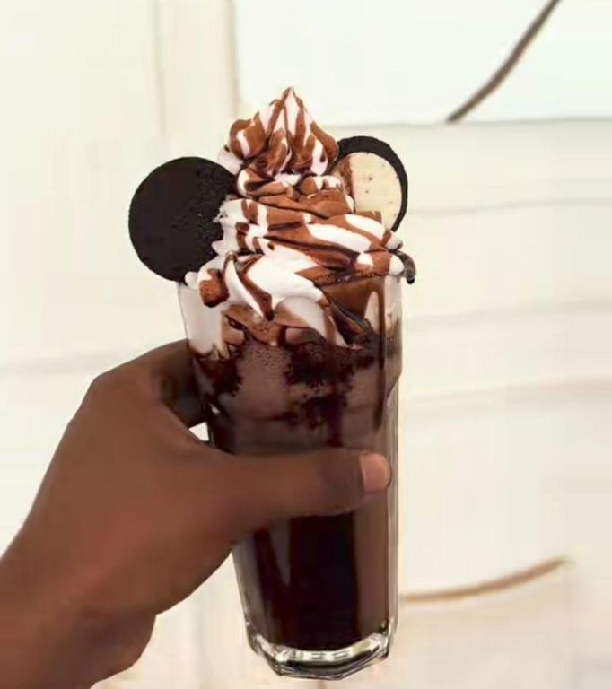 a hand holding a milkshake with oreos on it at Hayele hotel in Nazrēt