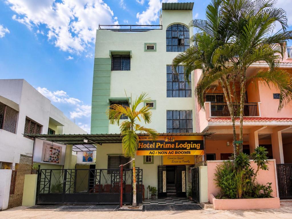 a building with palm trees in front of it at Hotel Prime Lodging in Aurangabad
